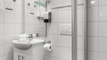 Een moderne badkamer met een wit wastafelmeubel, toilet en douche.