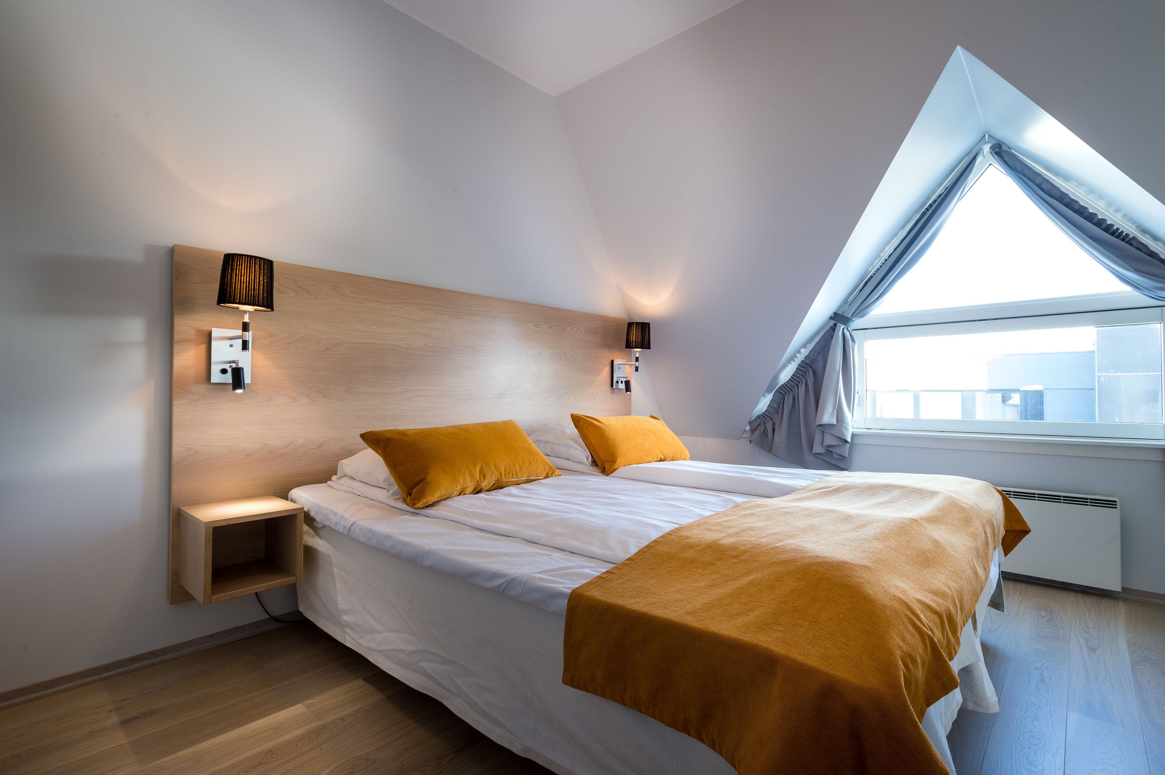Un dormitorio moderno con una cama grande, dos lámparas de noche, un estante empotrado y un ventanal con vistas.