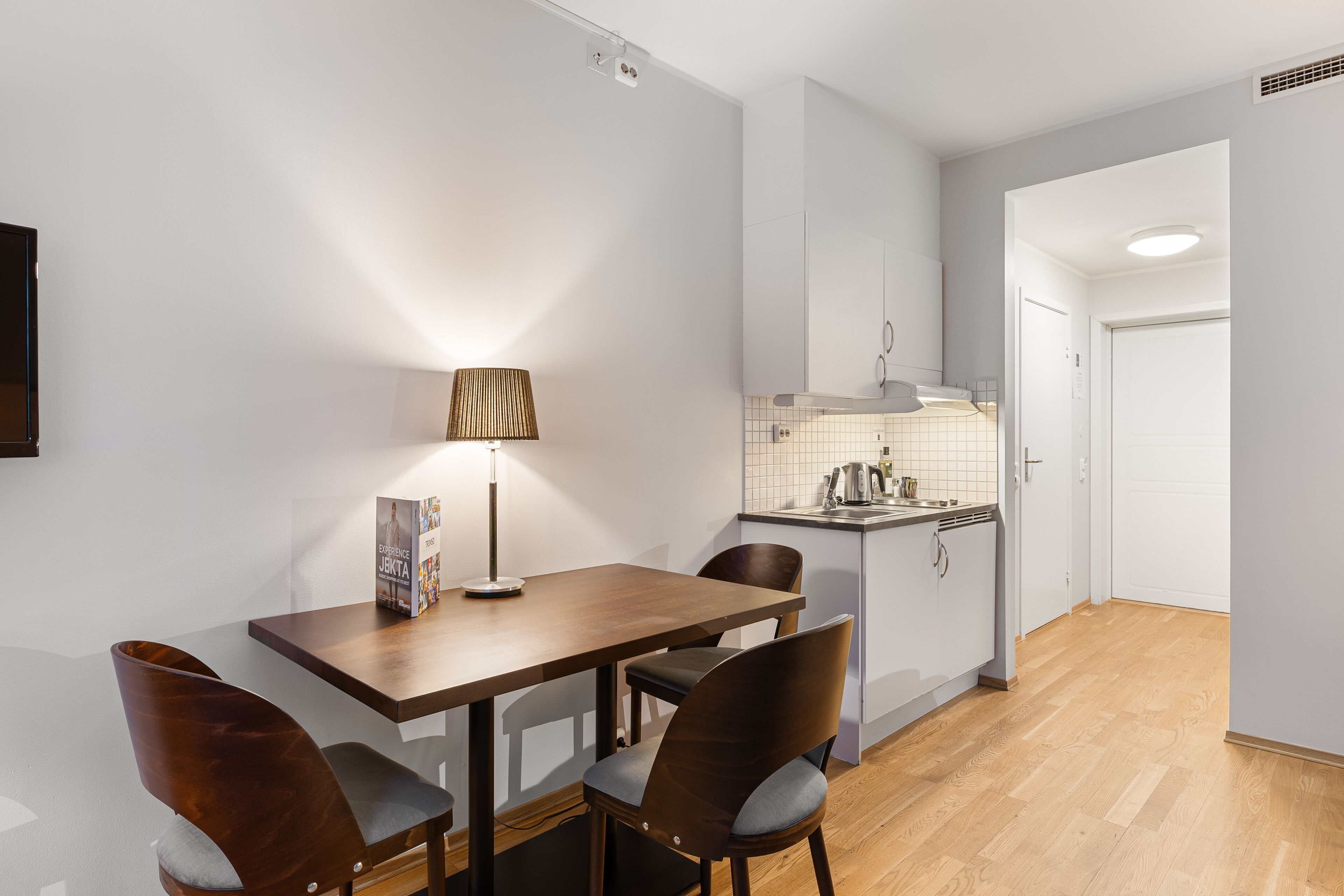 A modern kitchen with white cabinets, a wooden dining table, and two chairs.
