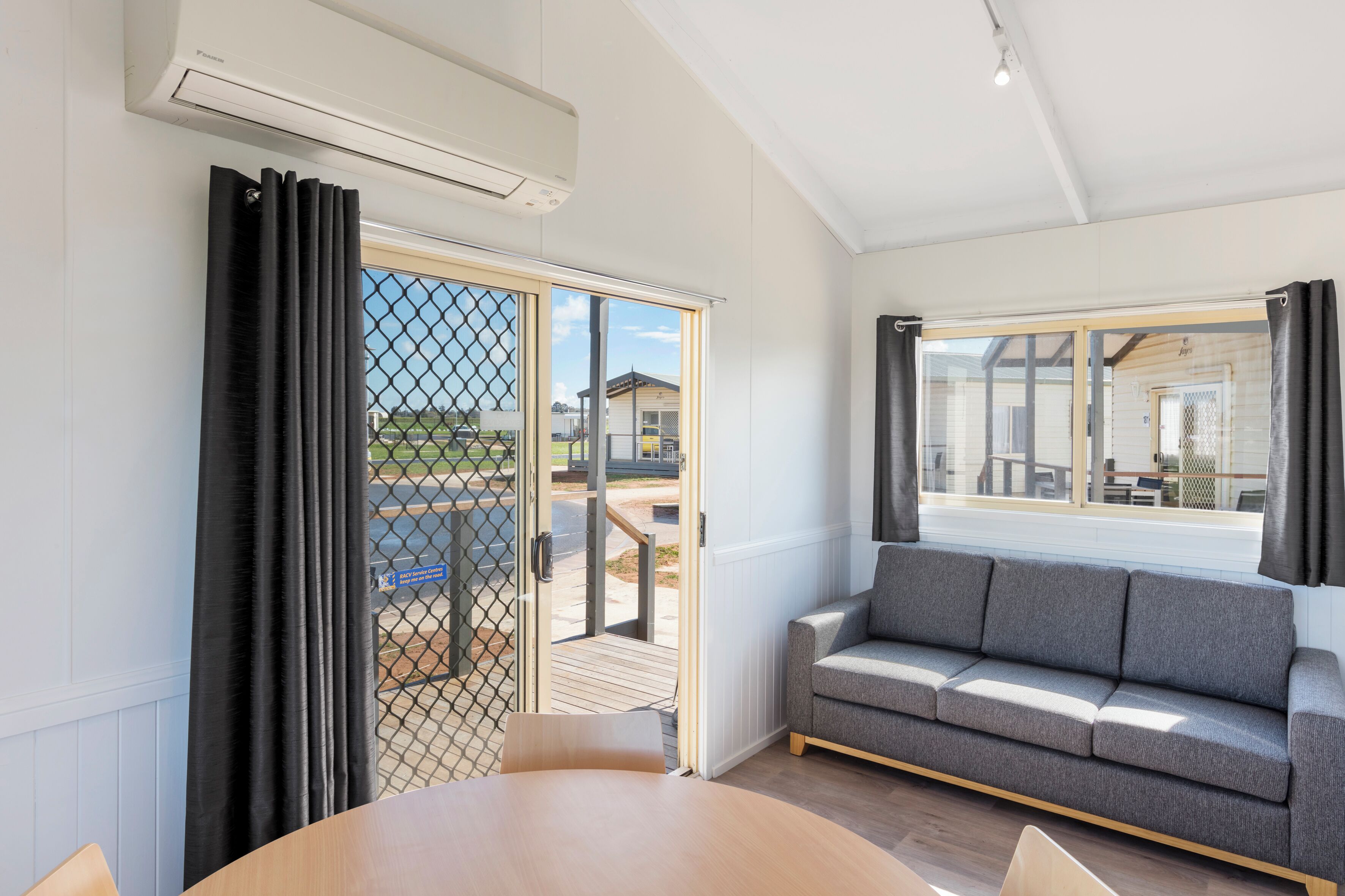 A modern room with a sofa, a table, and a sliding glass door leading to an outdoor area.