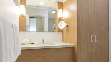 Un baño con tocador de madera, lavamanos, espejo y toalla.