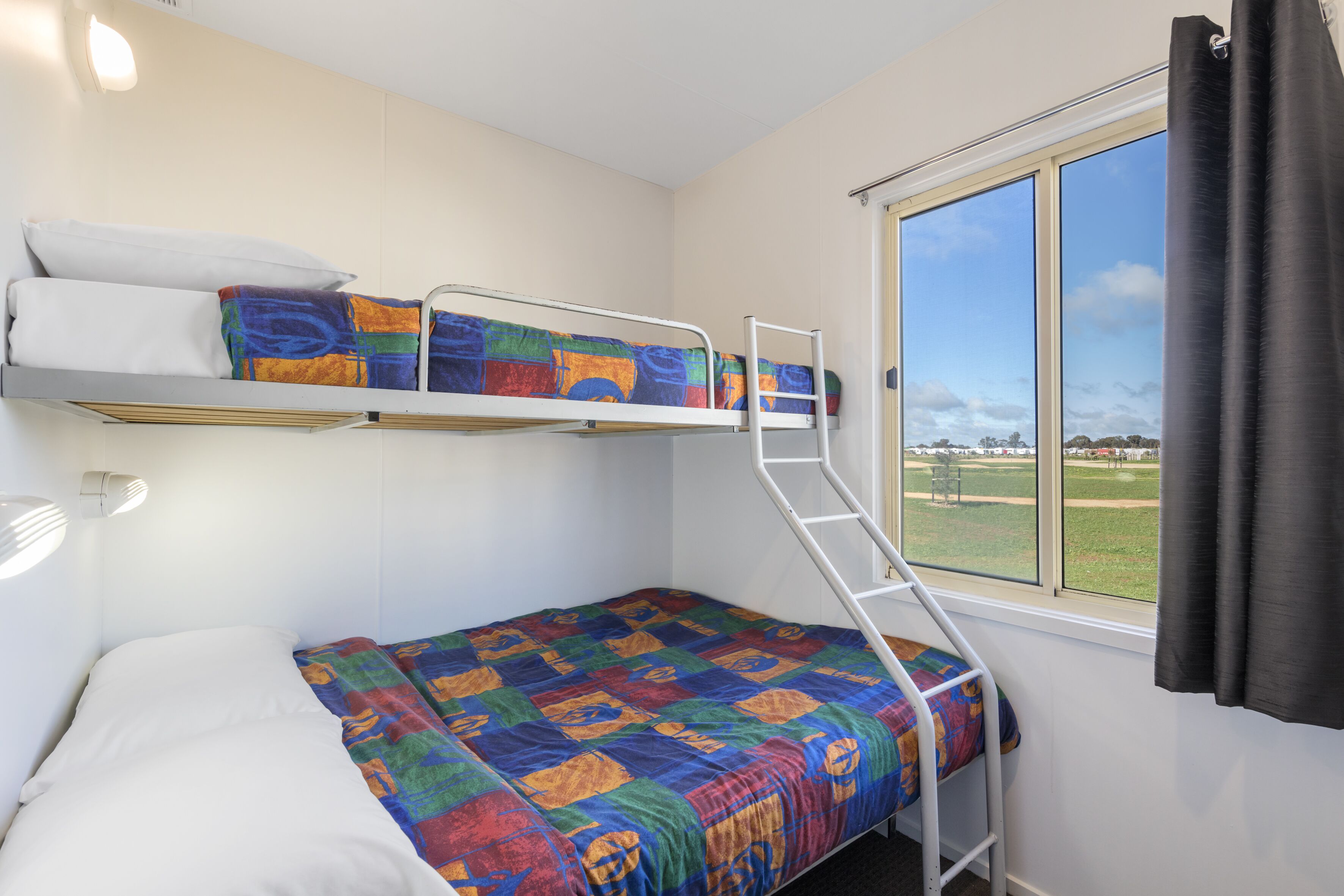 Habitación con literas y ventana con vistas a un campo.