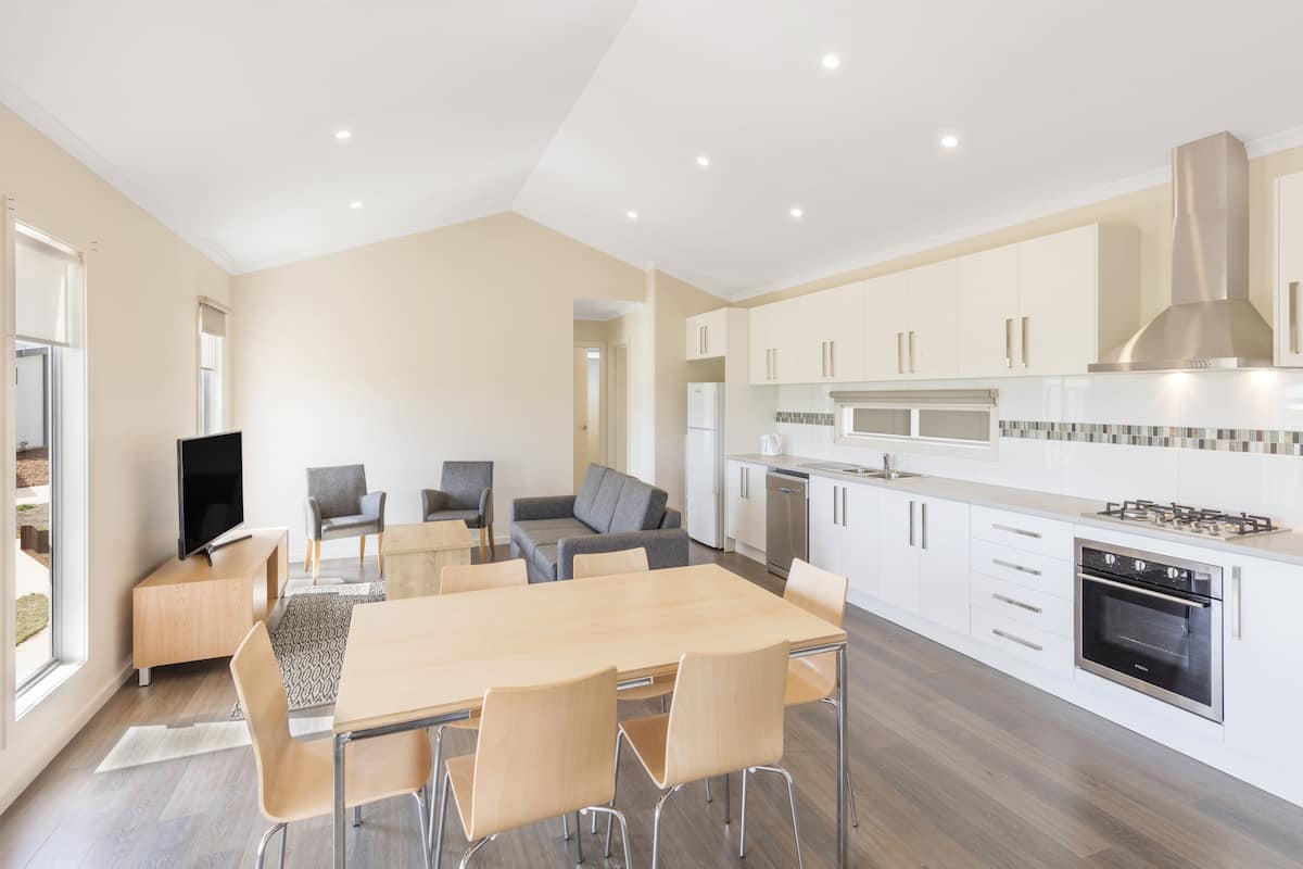 A modern kitchen with white cabinets, a built-in oven, and a stainless steel range hood.