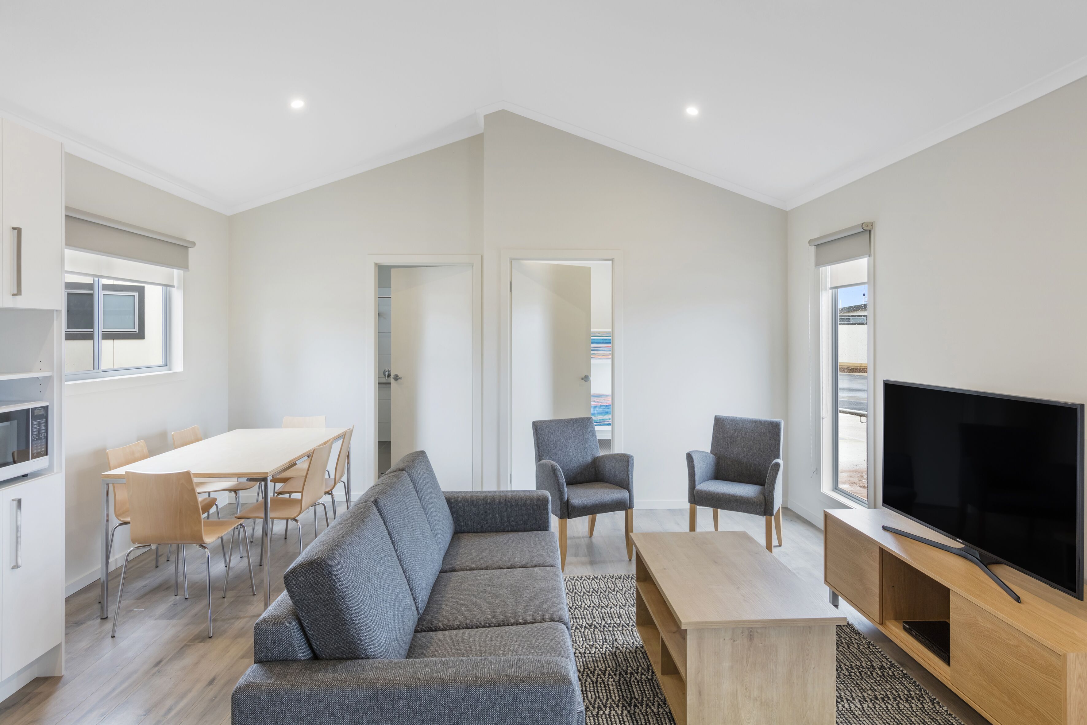 A modern living room with a sofa, TV, and dining area.