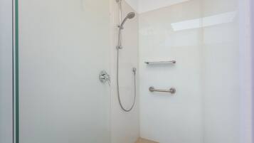 Un baño moderno con cabina de ducha de vidrio, ducha de mano y un perchero para toallas.