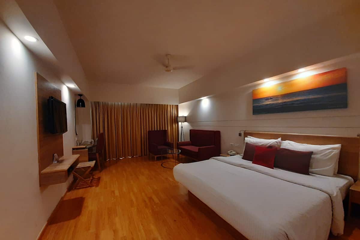 A hotel room with a large bed, a desk, a chair, a TV, and a painting on the wall.