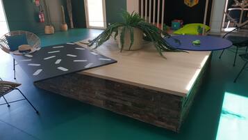 Une pièce chaleureuse avec une table en bois, une plante suspendue et un décor mural original.
