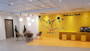 A reception area with a yellow wall, wicker chairs, a reception desk, and a map of travel routes.