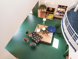 Un espace intérieur doté d’un sol vert, de meubles en bois et d’un espace salon circulaire.