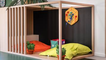 A wooden playpen with a black interior, a dartboard, and two potted cacti.