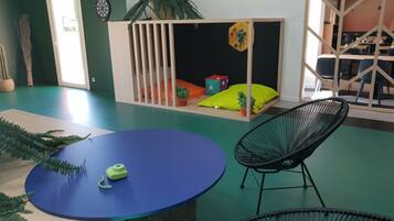 Relax in this vibrant room with a green floor, a colorful play area, and a large window.