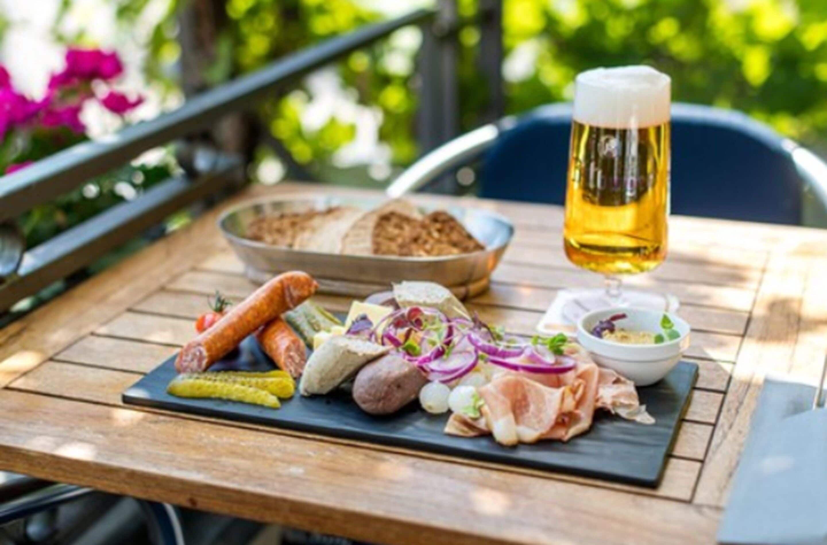 A wooden table with a variety of food items and a glass of beer.