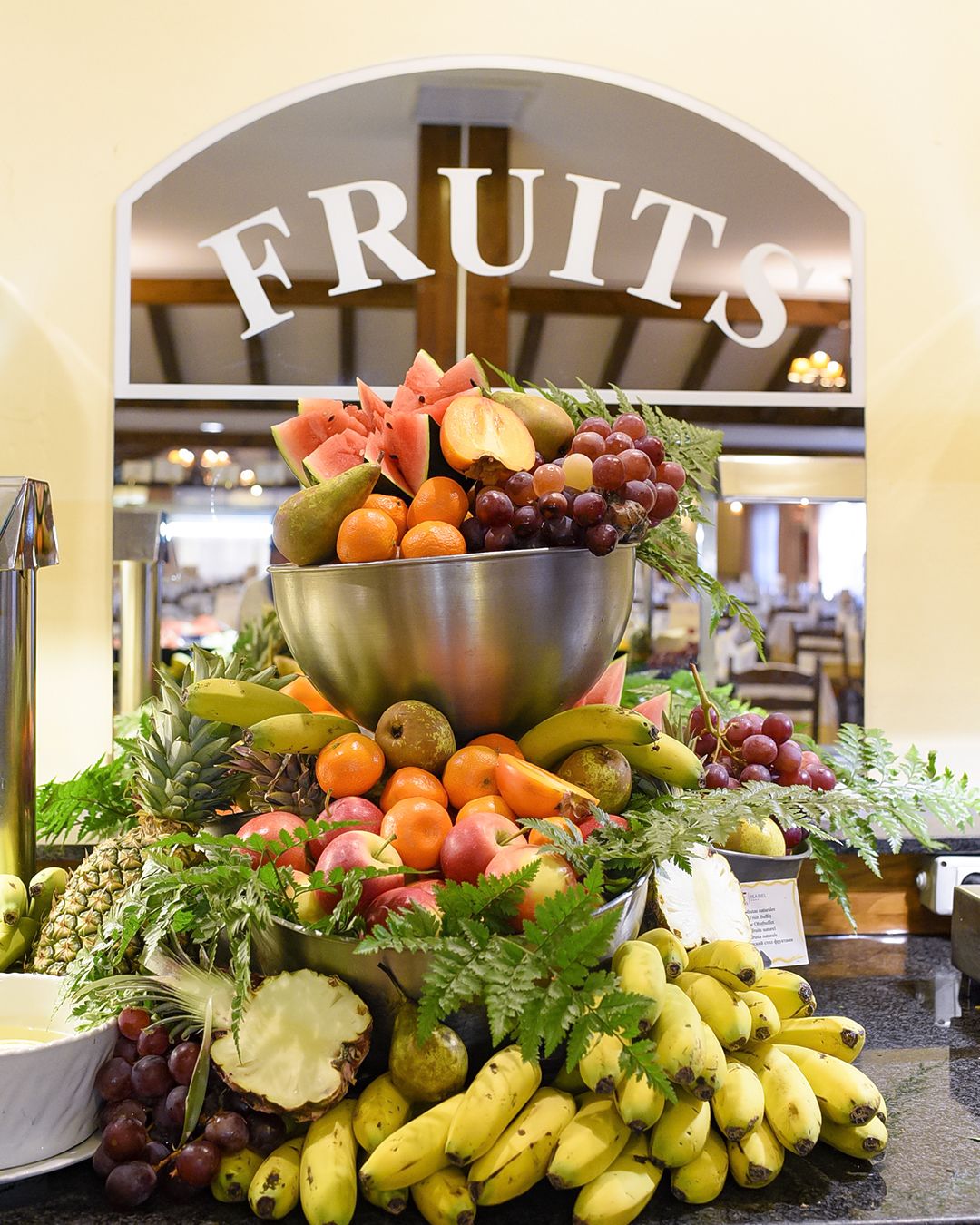 Un présentoir de fruits surmonté d’une pancarte indiquant « FRUITS ».