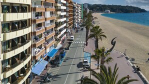 A coastal hotel with multiple balconies, a beach view, and a parking area with scooters. - Almirall Apartaments (Lloret de Mar)