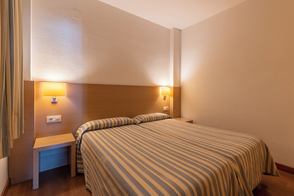 Ein Hotelzimmer mit einem Bett, zwei Nachttischen und zwei Wandlampen.
