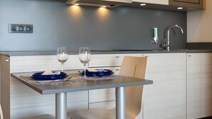 A modern kitchen with a dining table set for two, a microwave, and a sink. - Almirall Apartaments (Lloret de Mar)