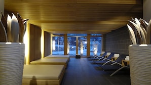 Un cuarto de spa con piso de madera, ventanas amplias y vistas a un paisaje nevado.