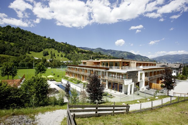 Un hotel moderno con una estructura de varios pisos, grandes ventanales y un paisaje verde circundante.