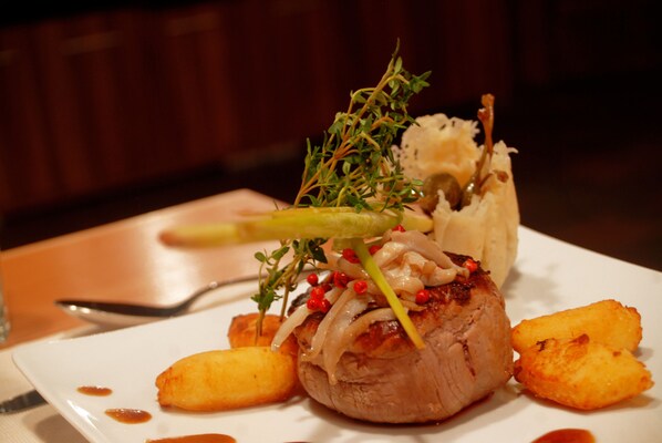 A plated dish with meat, vegetables, and a garnish on a white plate. - ACTIVE by Leitner’s - Nature & Lifestyle Hotel (Kaprun)