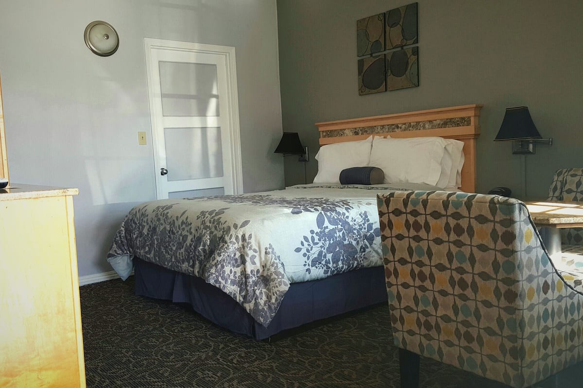 Une chambre d’hôtel avec un lit, une chaise, un bureau et une lampe.