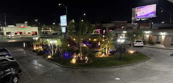 Una intersección bien iluminada con un restaurante Taco Bell, un letrero con vista a un jardín y una tienda T-Mobile.