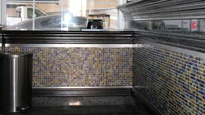 A subway station with tiled walls, a metal trash can, and a view of parked cars outside. - Garden View Inn (Fresno)