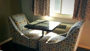 A small room with a bed, a table, and two chairs with a leaf pattern. - Garden View Inn (Fresno)