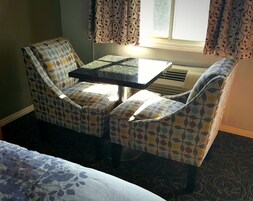 Una habitación pequeña con cama, una mesa y dos sillas con diseño de hojas.