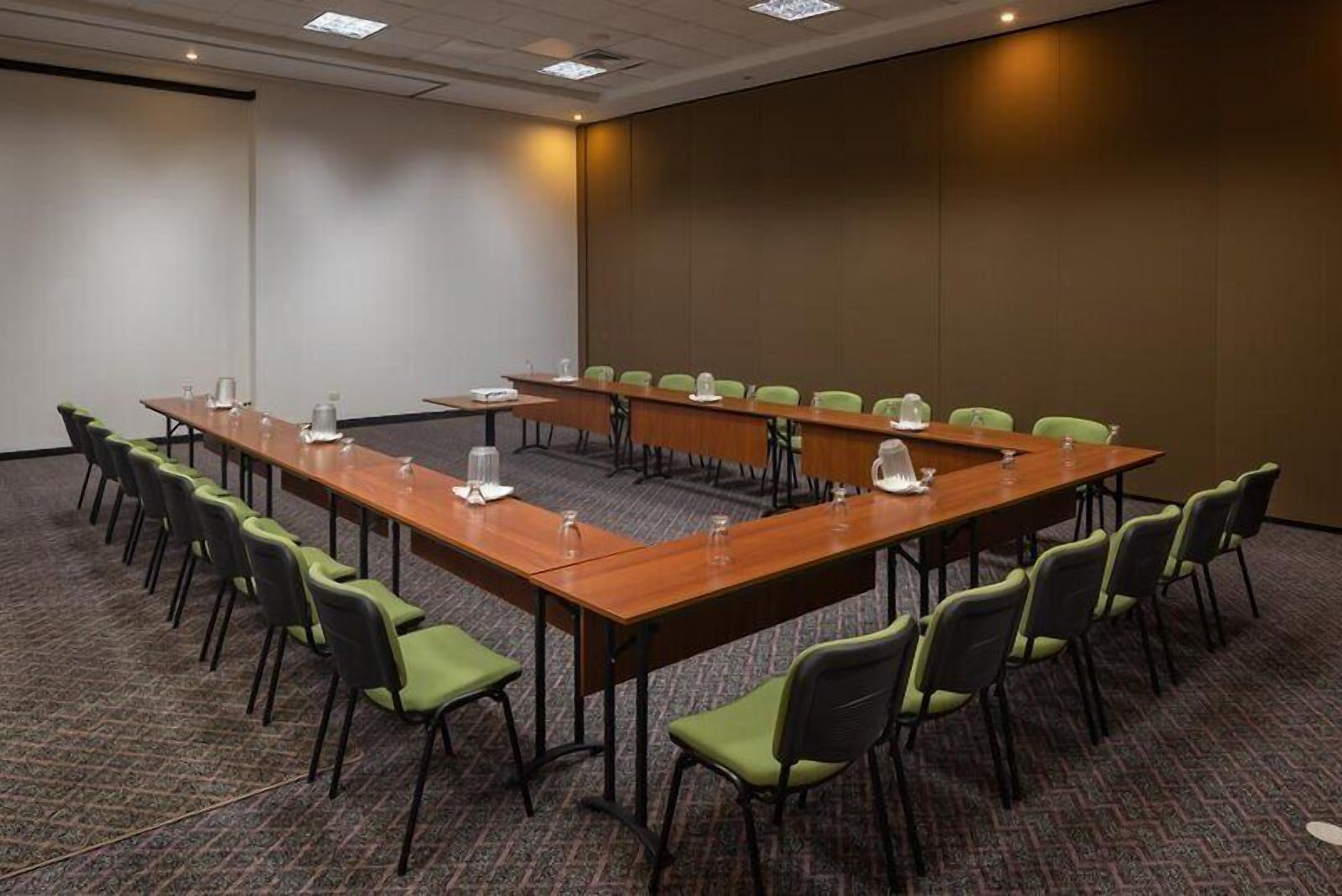 A conference room with a long table, multiple chairs, and a projector screen.