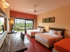 A hotel room with two beds, a balcony, a wooden table, and artwork on the wall.