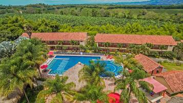 Un resort con piscina, palmeras y vista a las montañas.
