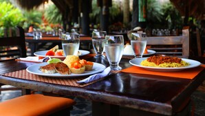 A restaurant table with plates of food, glasses of water, and a napkin. - Decameron Panaca All Inclusive (Quimbaya)