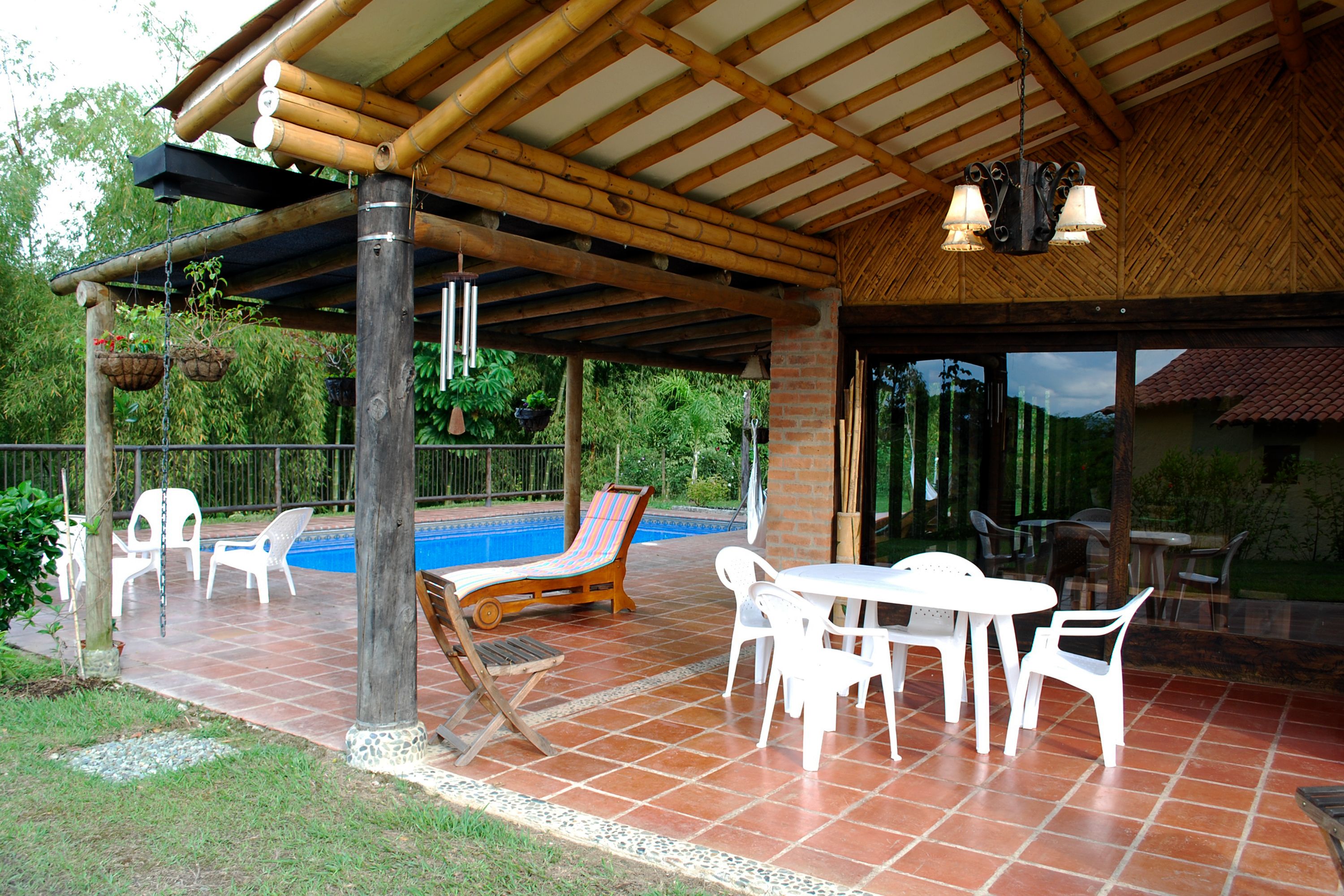 A covered outdoor area with a pool, lounge chairs, and a table with chairs.