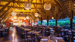 A restaurant with a thatched roof, wooden tables and chairs, and hanging spherical light fixtures. - Decameron Panaca All Inclusive (Quimbaya)