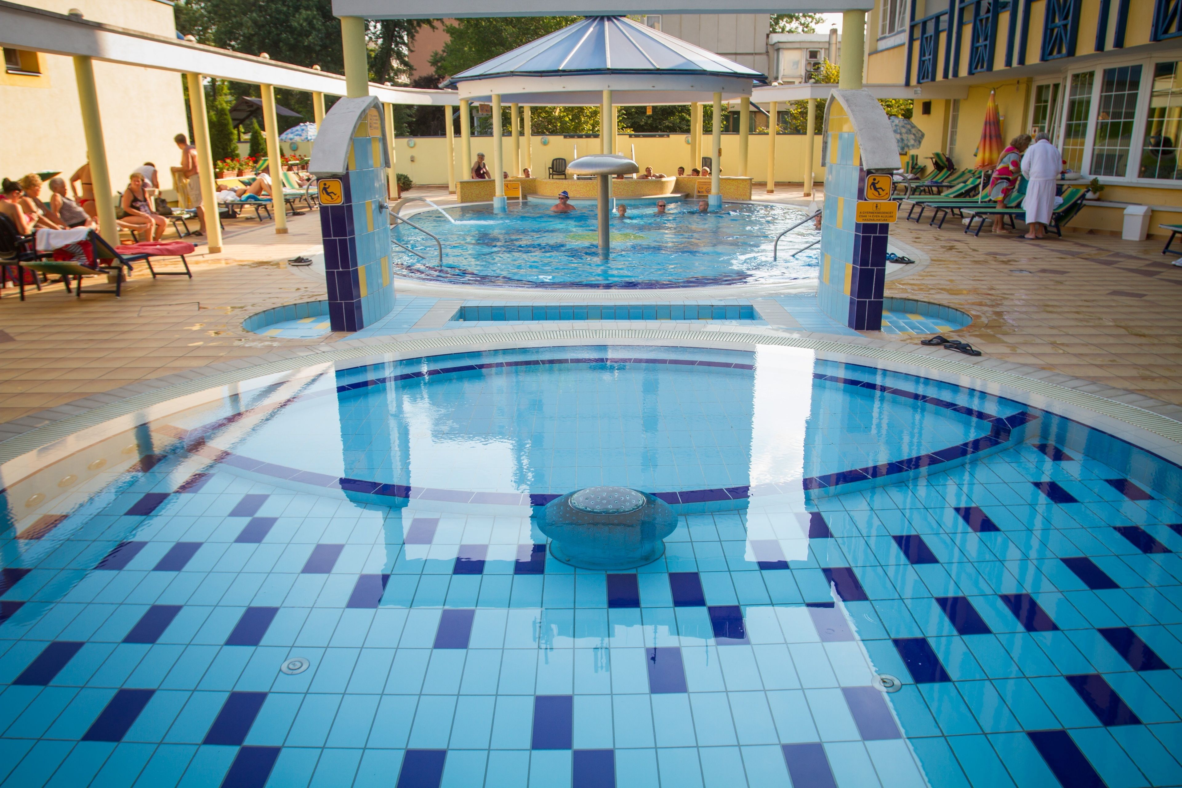 A swimming pool with tiled flooring and a central fountain.