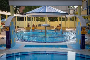 A swimming pool with a covered area and lounge chairs.