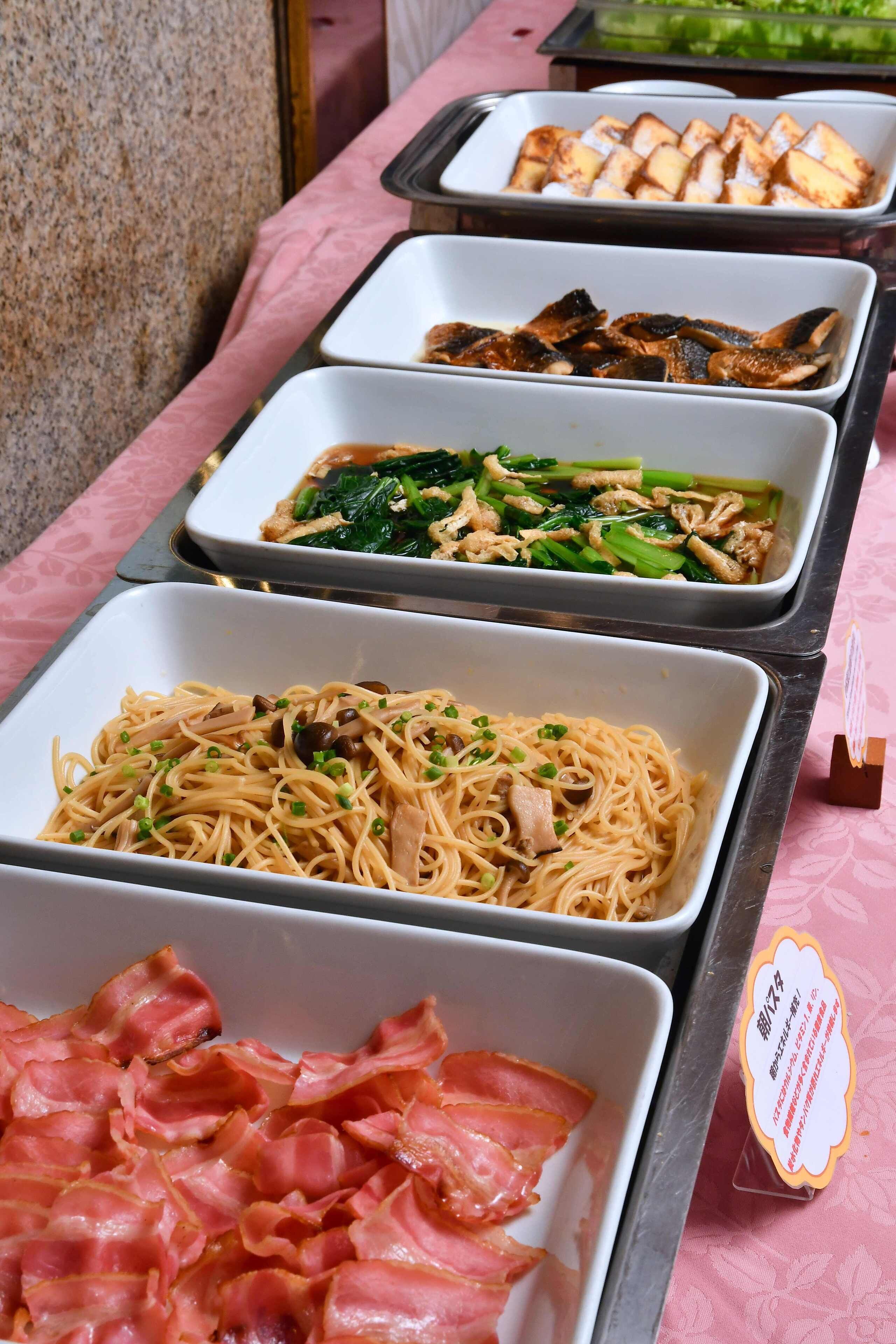 Una taula de buffet amb diferents plats, incloent aliments fregits, fesols i verdures.