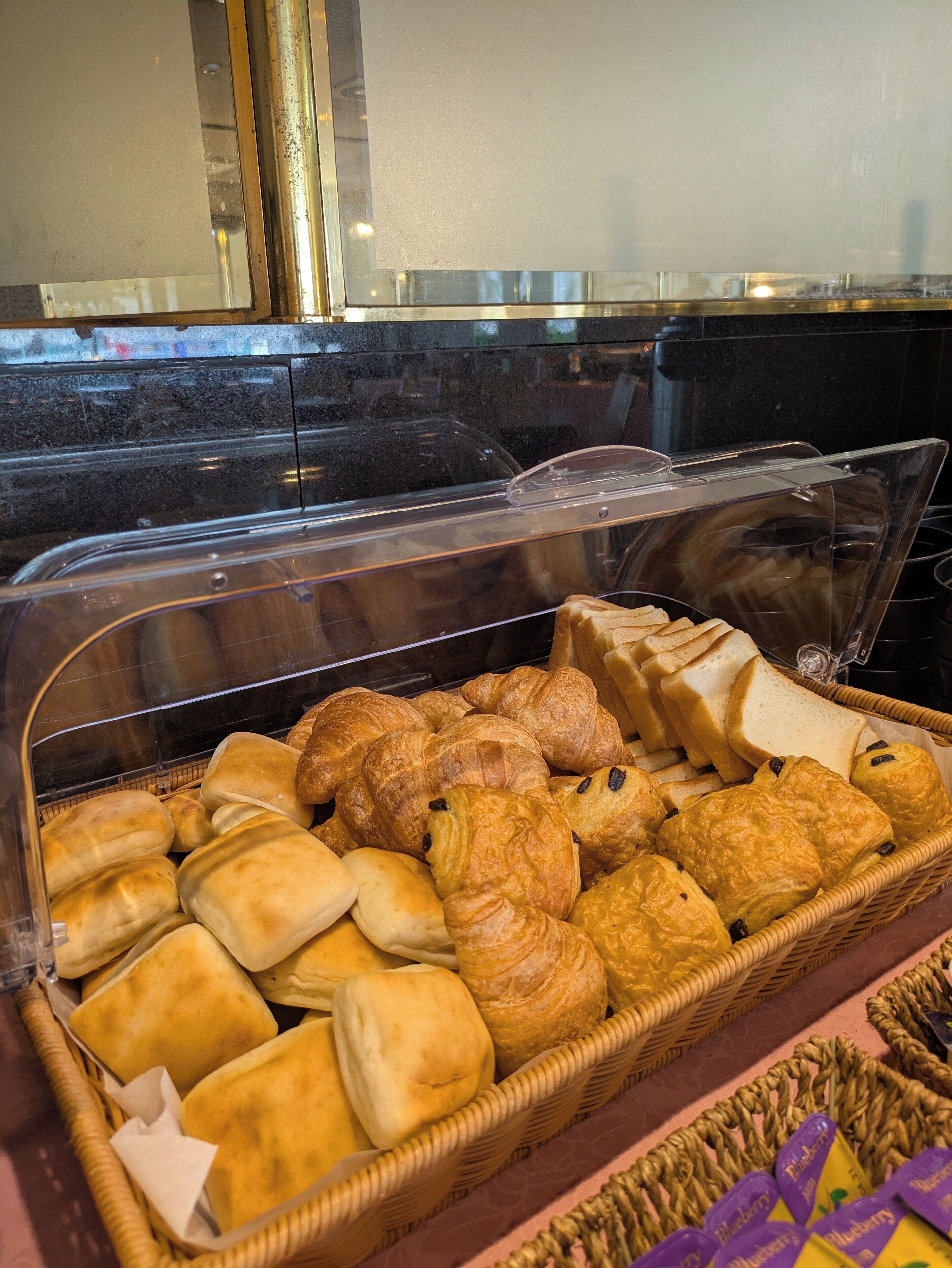 A display case filled with various baked goods including bread, rolls, and pastries.