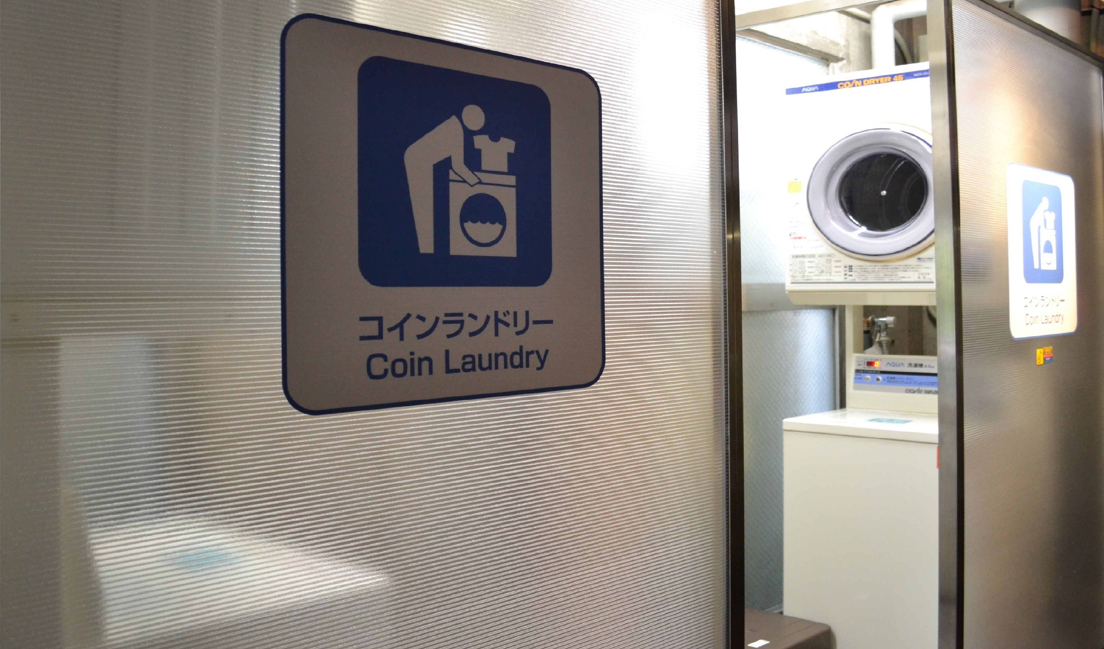 A coin laundry machine with a sign indicating its purpose.