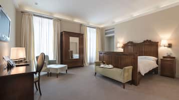Ein Hotelzimmer mit Schreibtisch, Stuhl, Sofa, Bett, Kleiderschrank und Spiegel.