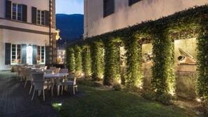 An outdoor patio with tables and chairs, surrounded by a wall covered in ivy. - Grand Hotel della Posta, WorldHotels Distinctive (Sondrio)