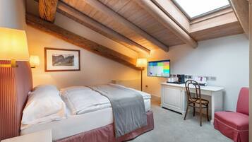 A bedroom with a bed, desk, chair, and a large window.