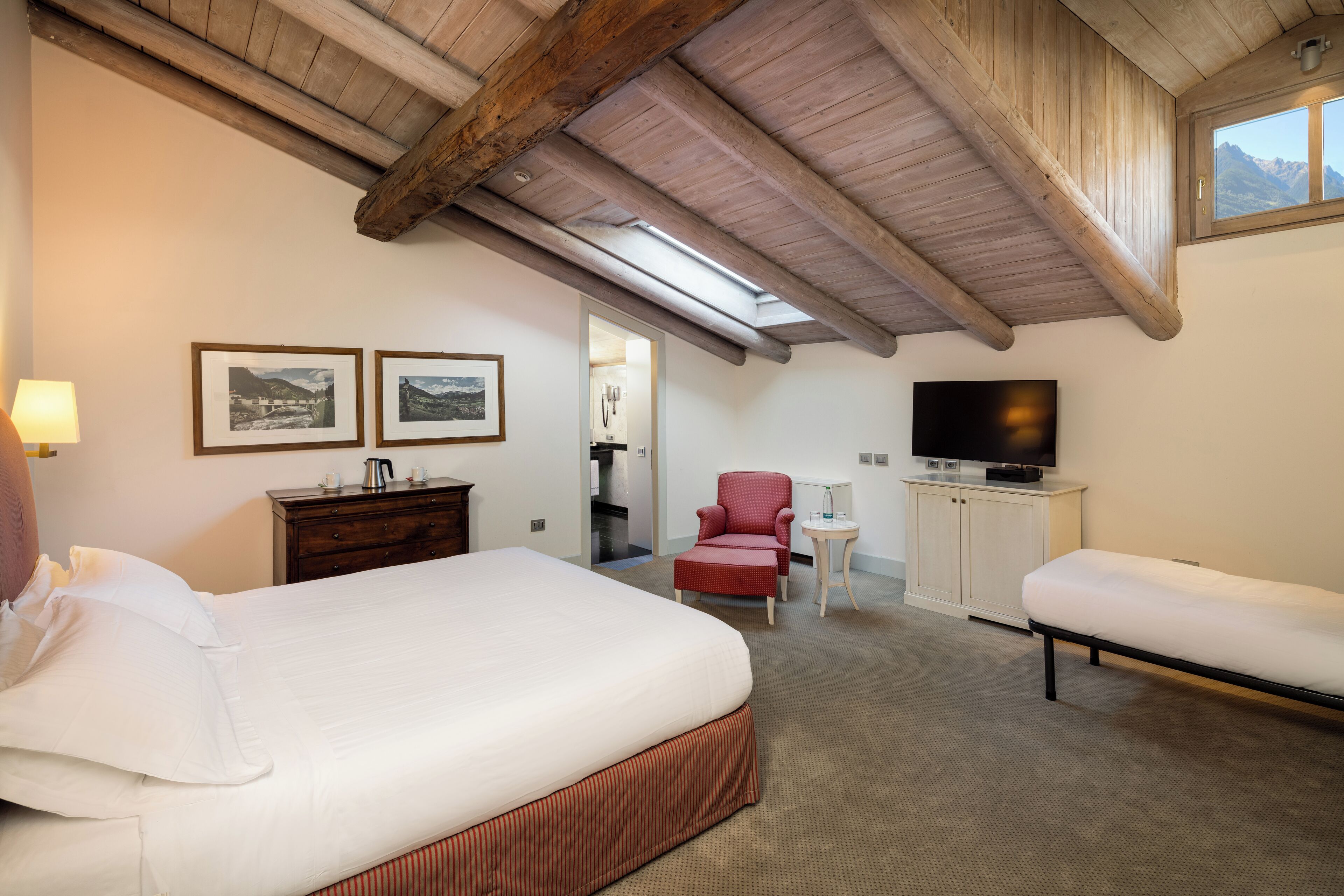 Habitación de hotel con una cama grande, un escritorio con silla, televisión y cuadros en la pared.