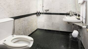 A bathroom with a toilet, a shower, and a sink.