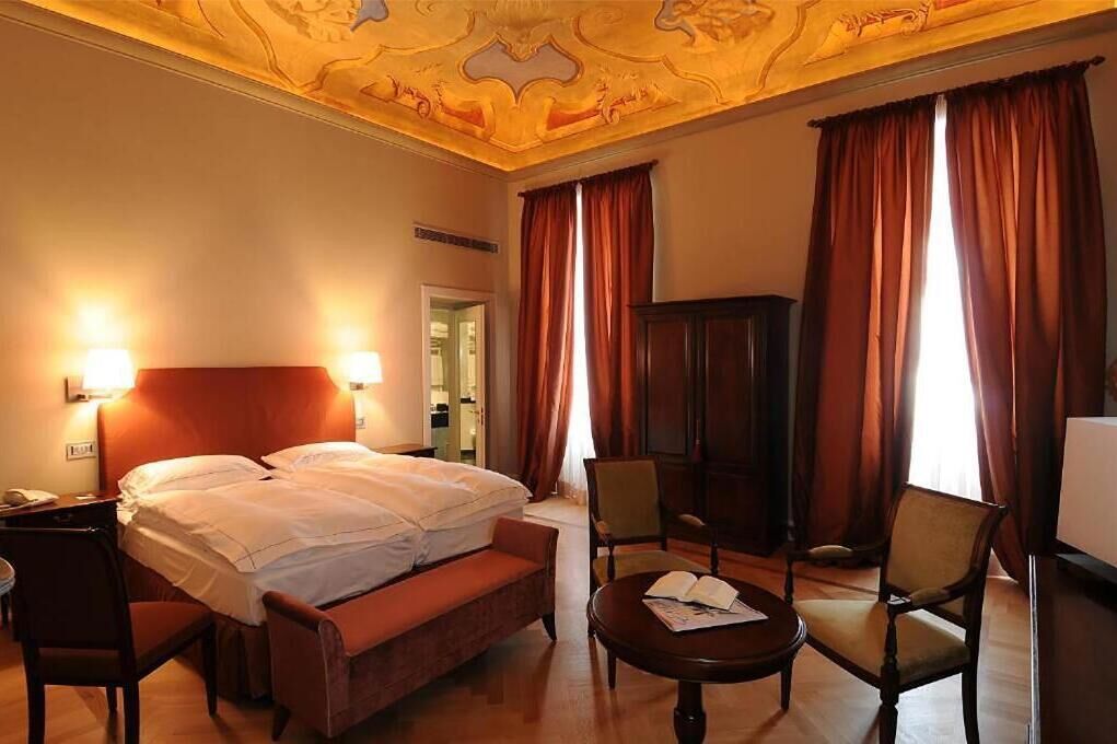 Habitación de hotel con una cama grande, dos sillas, una mesita y un armario.