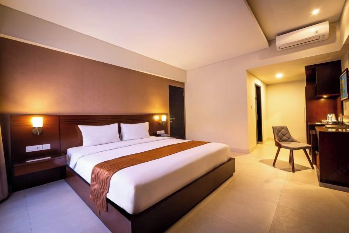 Una habitación de hotel moderna con una cama grande, mesitas de noche, un escritorio y un aire acondicionado.