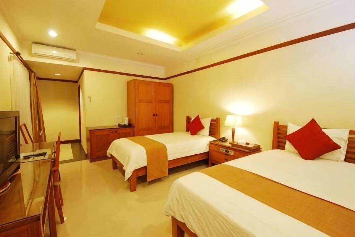 A hotel room with two beds, a desk, a TV, and a wardrobe.