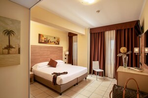 Una camera d'albergo con un letto, una scrivania, una sedia, una lampada e un quadro appeso al muro.