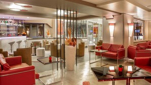 A modern lounge area with red leather sofas, glass tables, and a bar with a variety of bottles. - Hotel Domidea (Rome)