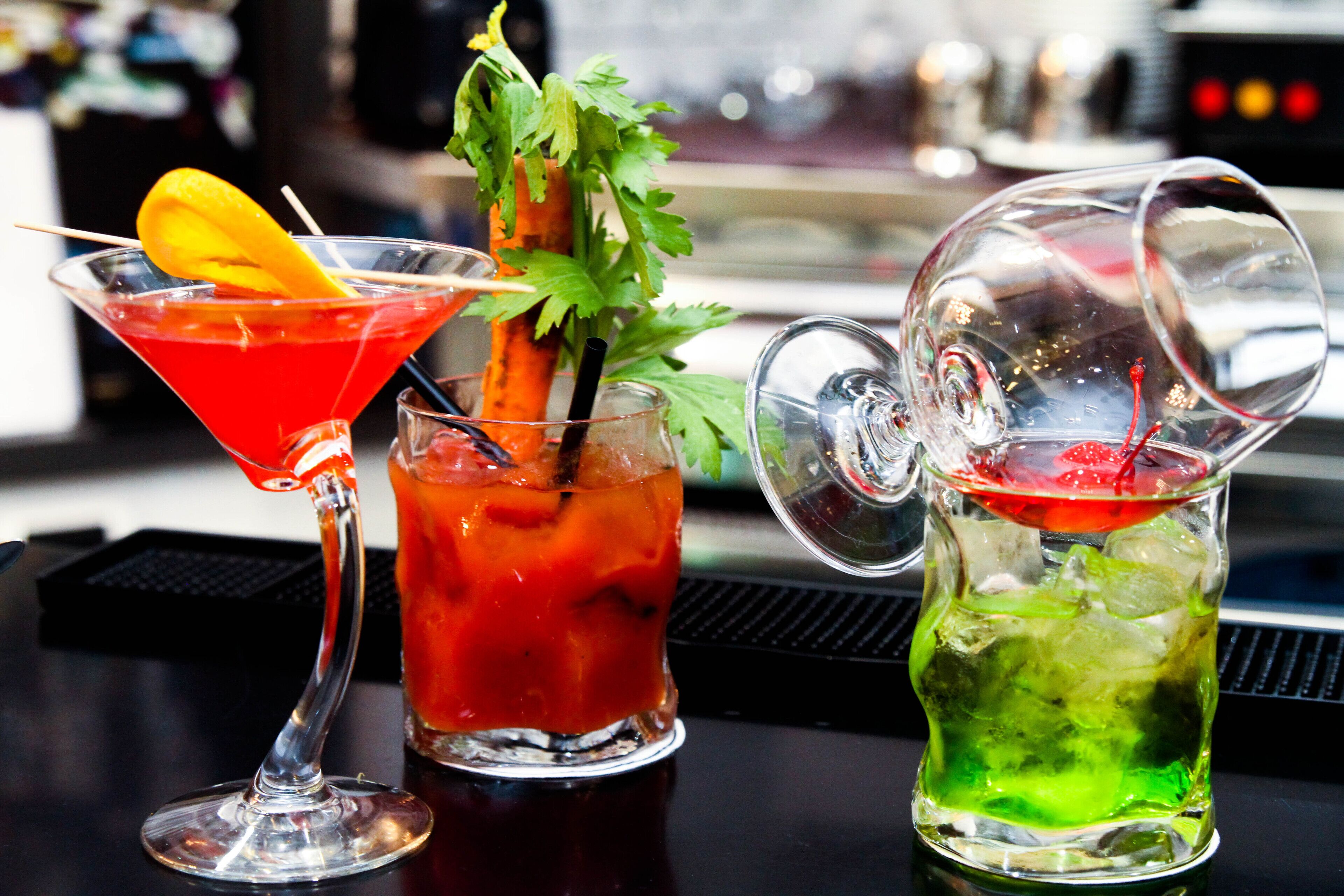Three cocktails on a bar counter with a blurred background.